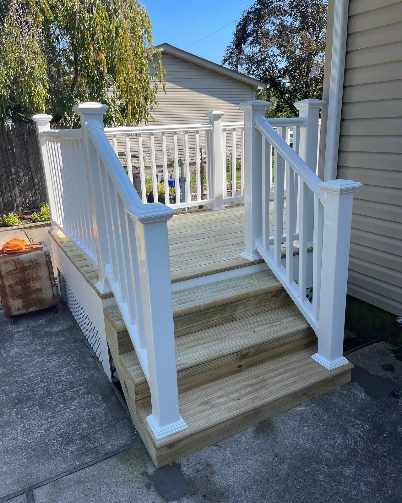 Finished deck with white vinyl railings and wood steps