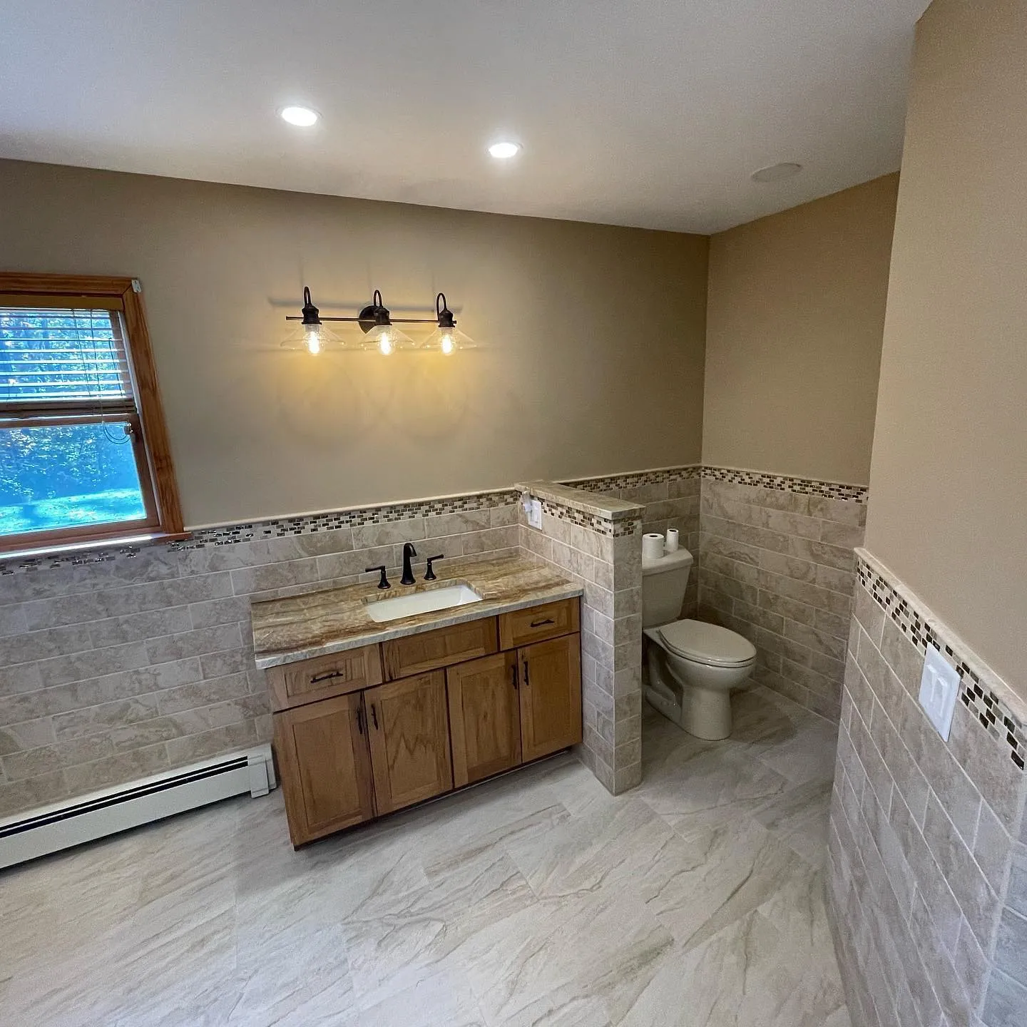 Bathroom with stone tile, wood vanity, and mosaic accent